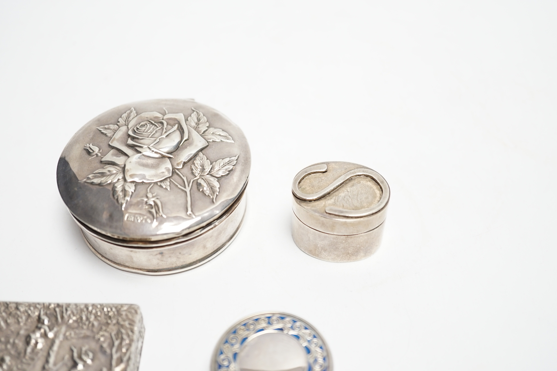 An Edwardian silver circular trinket box, embossed with a rose, Chester, 1909, 65mm, two modern pill boxes, silver and 800 standard with enamel and a modern Italian silver pill box.